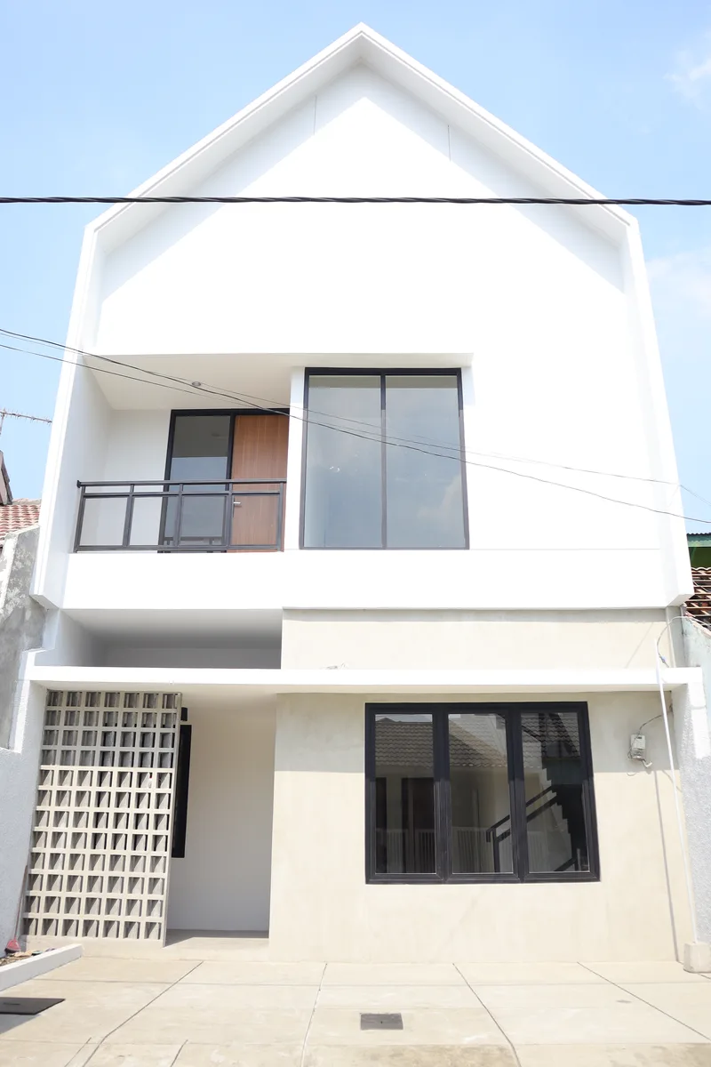 Fasad rumah dua lantai bergaya Skandinavia hasil renovasi dengan atap pelana, balkon, jendela kaca besar, dan dinding roster