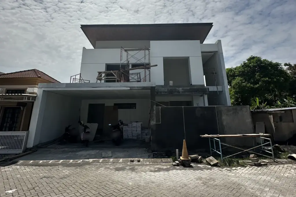 Rumah dua lantai tahap finishing dengan perancah di fasad dan tumpukan keramik di carport, proyek Madina Build di Citra Garden Sidoarjo